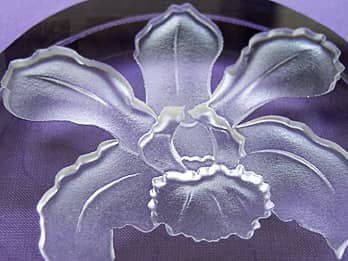ガラス製ペーパーウェイトに彫刻したランの花のクローズアップ画像