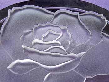 ガラス製ペーパーウェイトに彫刻した、ばらの花のクローズアップ画像