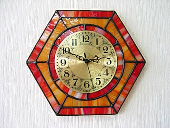 時計針の軸を中心にして、六角形のステンドグラス部を少しだけ回して固定した場合のステンドグラス製の掛け時計 オレンジ（六角形）