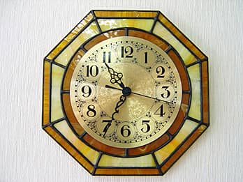 時計の針を取り付ける軸を中心にして、八角形のステンドグラス部を少しだけ回して固定した場合のステンドグラス製の掛け時計 キャラメルイエロー（八角形）