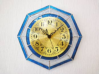 時計の針を取り付ける軸を中心にして、八角形のステンドグラス部を少しだけ回して固定した場合のステンドグラス製の掛け時計 マリンブルー/クリア（八角形）