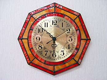 時計の針を取り付ける軸を中心にして、八角形のステンドグラス部を少しだけ回して固定した場合のステンドグラス時計 オレンジ（八角形）