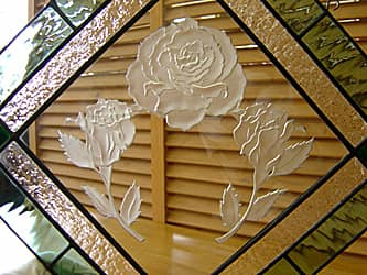 バラの花を彫刻したエッチングガラスの周りを、ステンドグラスで装飾した壁飾り